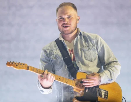 Zach Bryan, 6 feet tall country star, performing on stage with his guitar. zach bryan height